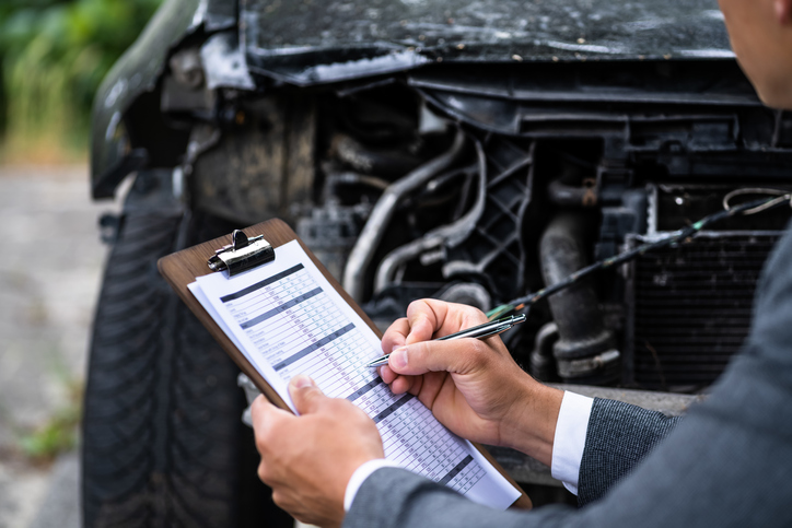 insurance company adjuster assessing damage to car